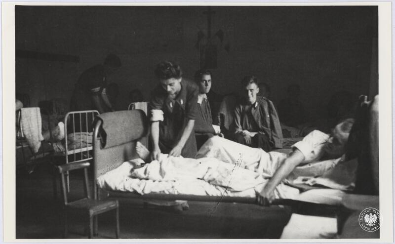 Ranni powstańcy z  oddziału AK i sanitariuszki w sali jednego ze szpitali powstańczych IV Zgrup. Gurt przy ul. Złotej 22 lub 58, ewent. przy ul. Chmielnej, fot. H. Śmigacz, z zasobu IPN, sygn. IPNBU-2-21-32-1-1