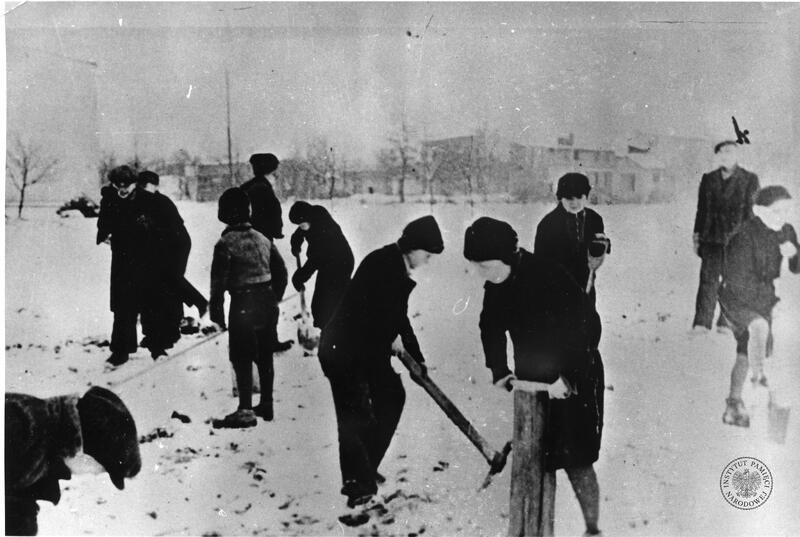 Dzieci - więźniowie niemieckiego obozu dla dzieci i młodzieży polskiej przy ul. Przemysłowej w Łodzi, wykonujące prace terenowe. Fotografia wykonana w okresie zimowym, z zasobu AIPN, sygn. IPNLd-1-2-26-20
